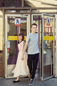 Portrait of smiling young woman standing on entrance