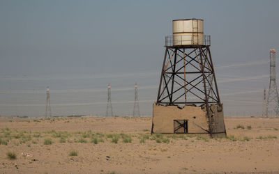 Water tower on landscape against sky