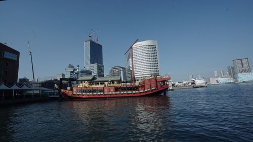 Nautical vessel on river by buildings against sky in city