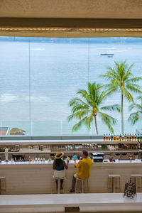 Couple drinking cocktails at a bar during vacation looking out over the ocean