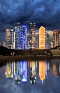 Illuminated modern buildings and burj qatar by river at night