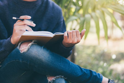 Midsection of man sitting with book