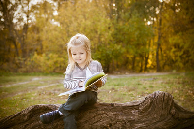 Girl reading book while sitting on tree