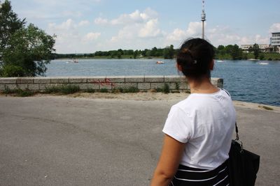 Rear view of woman standing on river against sky