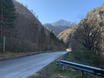 Road leading towards mountains against clear sky