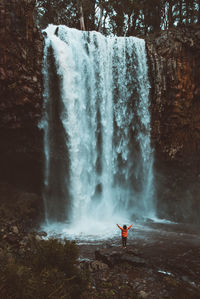 Scenic view of woman standing by waterfall