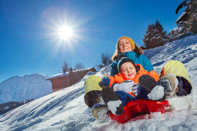 Rear view of woman sitting on snow