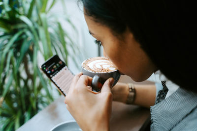 Woman drinking a cup of coffee and using mobile