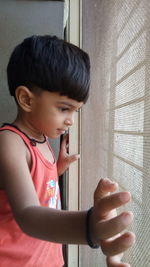 Boy looking through window at home