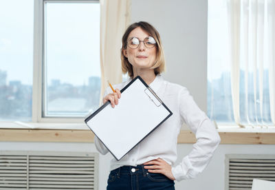 Portrait of young businesswoman using digital tablet while standing in office