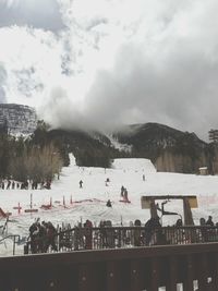 People on mountain against cloudy sky