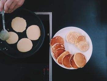 Cropped hand of person cooking pancakes on stove