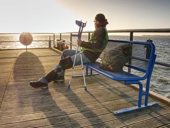 Hurt man having rest, looking into distance and meditating. person watching sunset against blue sea