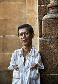 Portrait of a smiling young man holding wall