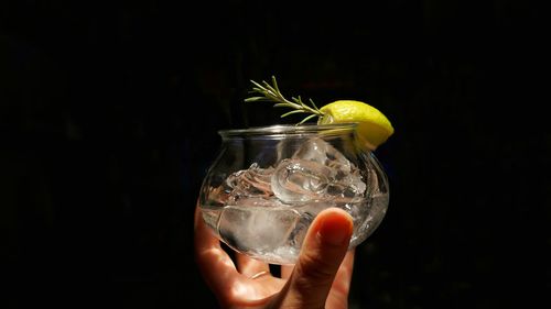 Close-up of hand holding drink against black background