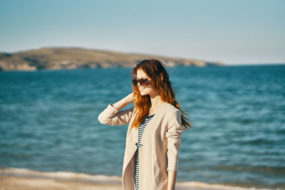 Woman standing by sea against sky