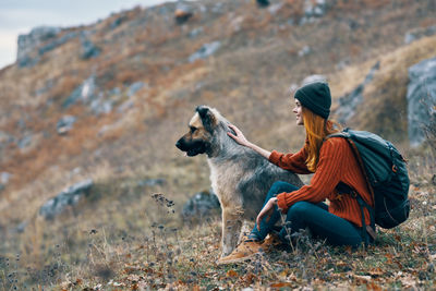 Side view of woman with dog sitting outdoors