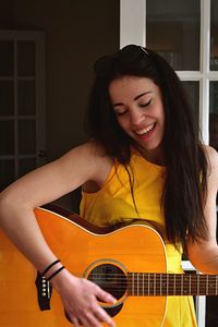 Happy young woman playing guitar