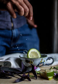 Cropped image of hand throwing lemon slice in cup