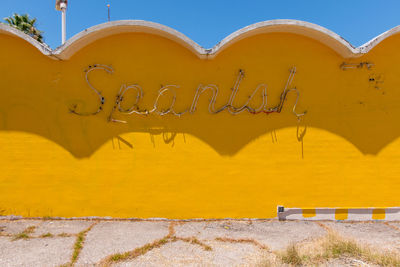 Text on yellow wall during sunny day