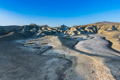 Scenic view of arid landscape against clear blue sky