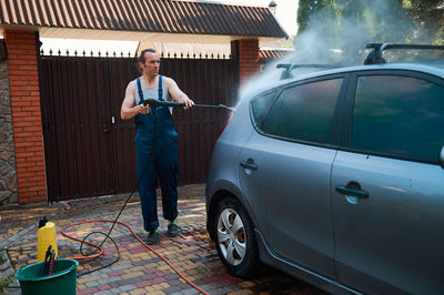 Side view of man standing in car