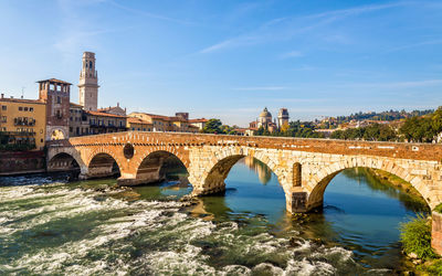 Arch bridge over river against buildings