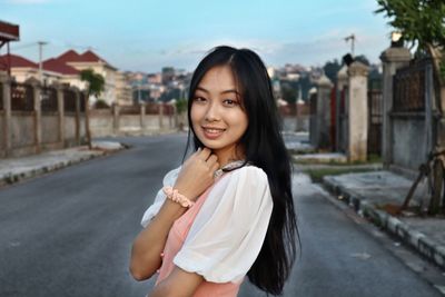 Portrait of smiling young woman standing in city