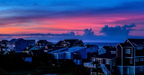 Houses and buildings against sky during sunset