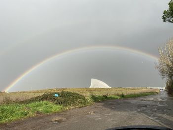Rainbow over wet road against sky