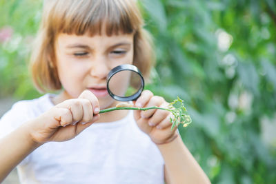 Girl looking at slug through magnifying glass