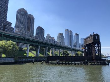 Bridge over river by buildings against sky in city