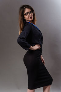 Portrait of smiling young woman standing against wall