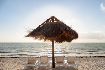 Thatched roof on beach against sky