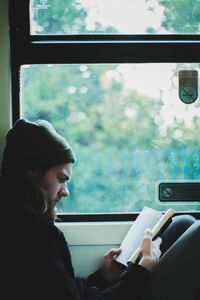 Man reading book while sitting in bus