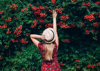 Low angle view of girl with red flowering plants