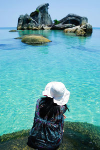 Rear view of woman sitting against sea