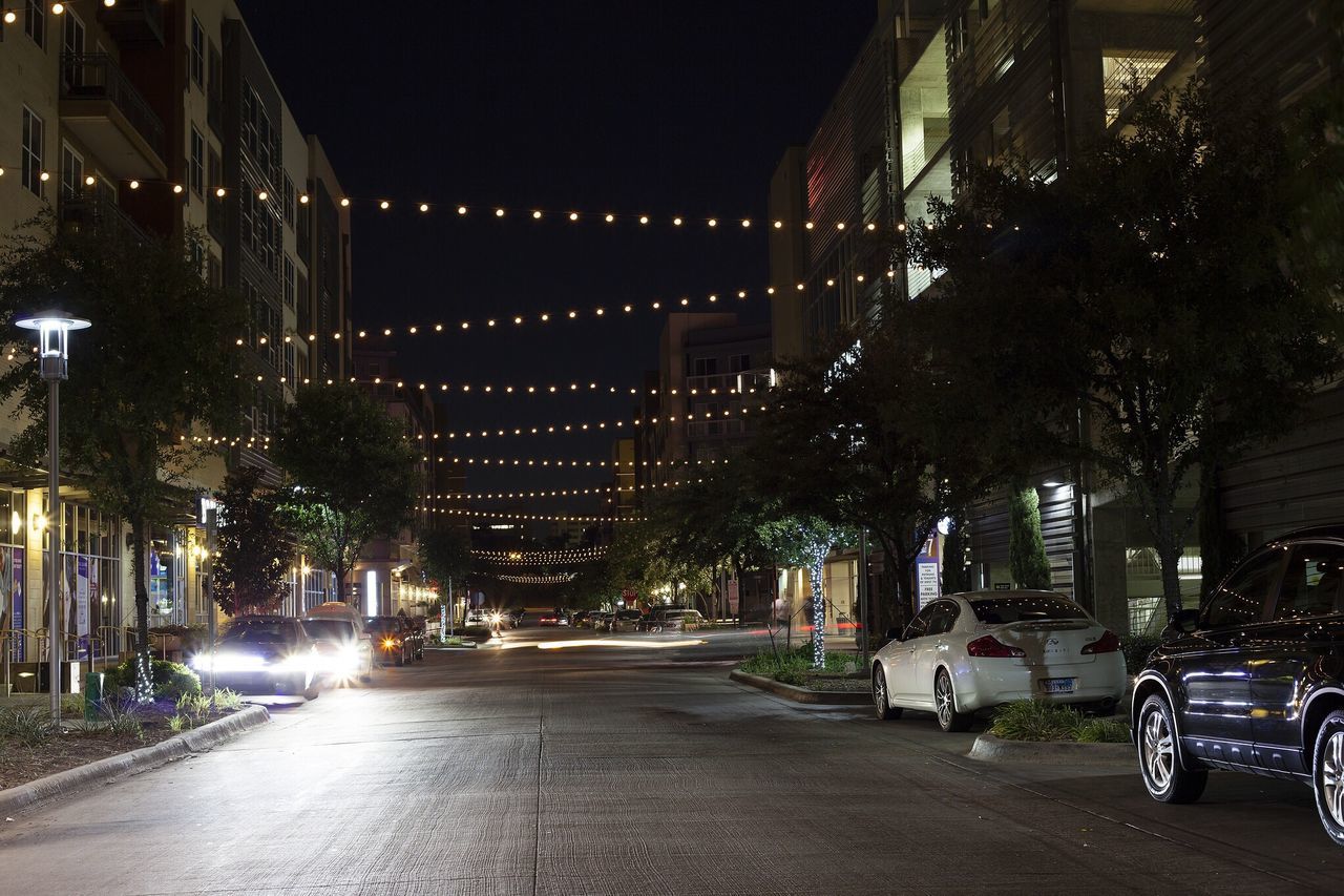 architecture, illuminated, built structure, building exterior, night, city, transportation, street, the way forward, street light, road, car, land vehicle, lighting equipment, city life, city street, mode of transport, diminishing perspective, incidental people, outdoors