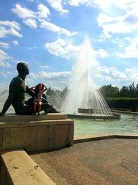 Girl sitting on statue against fountain