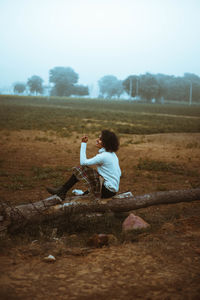 Side view of woman sitting on field