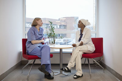 Female doctors sitting in hospital and talking to each other