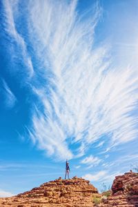 Low angle view of man standing on rock against sky