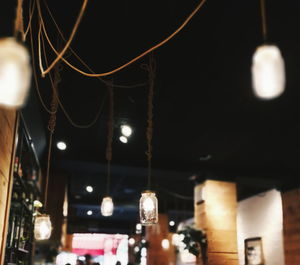 Low angle view of illuminated light bulb hanging at night