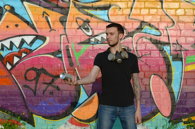 Full length of man standing against graffiti wall