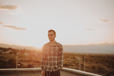 Man standing on terrace against sky during sunset