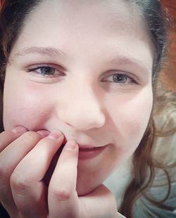 Close-up portrait of smiling girl with hand on chin