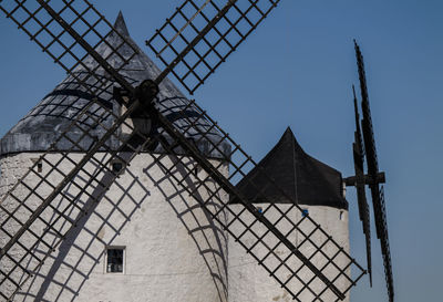 Low angle view of traditional white windmills in castilla la mancha, spain, against clear blue sky