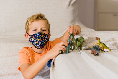 Portrait of boy wearing mask playing with toy at home