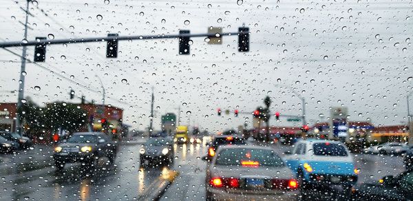 Cars on road seen through wet glass window in rainy season