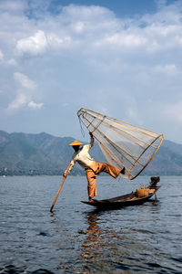 Man holding fishing boat in sea against sky